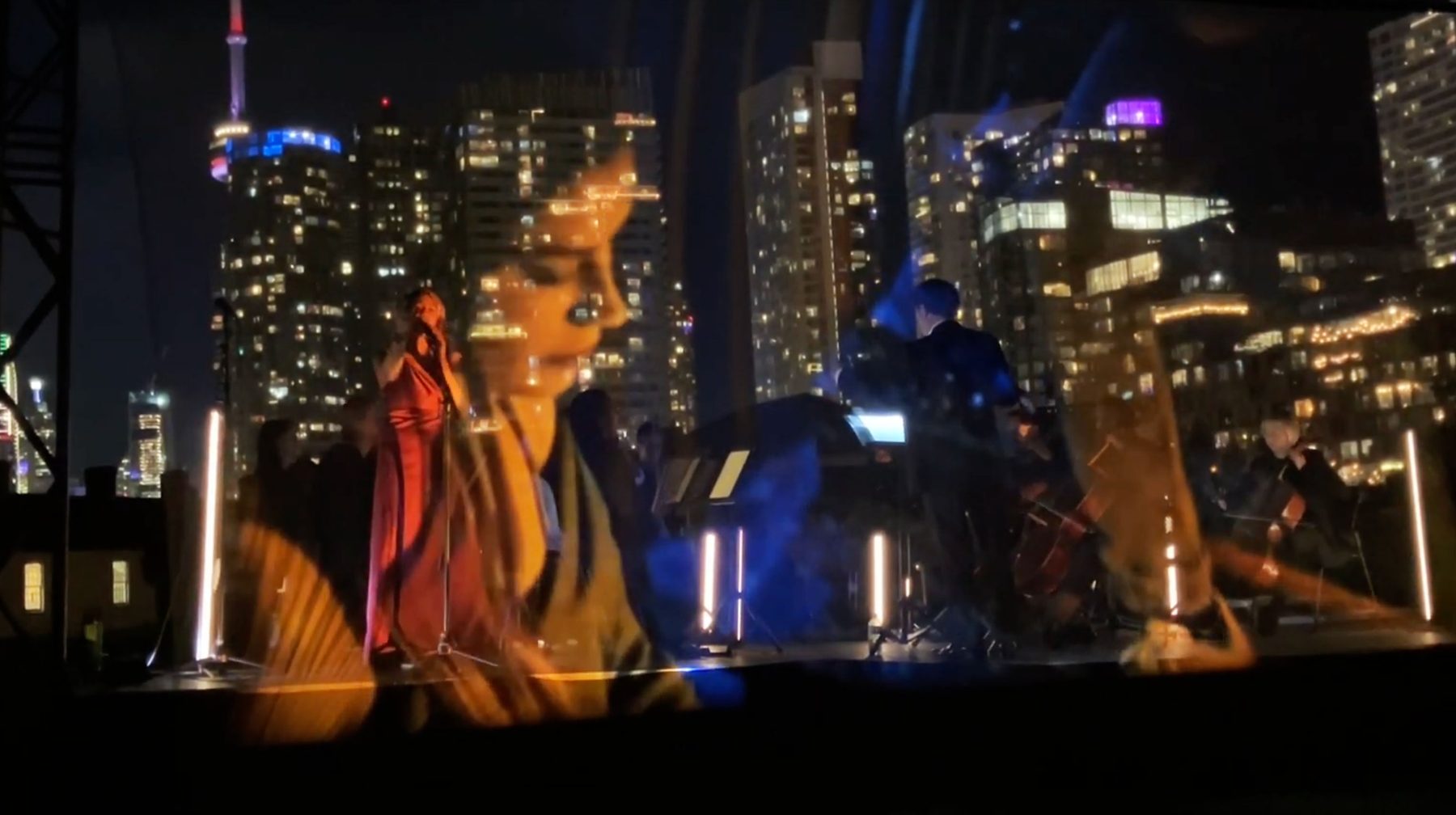 450 drones forming a figure over the Toronto skyline, with the holographic orb stage below