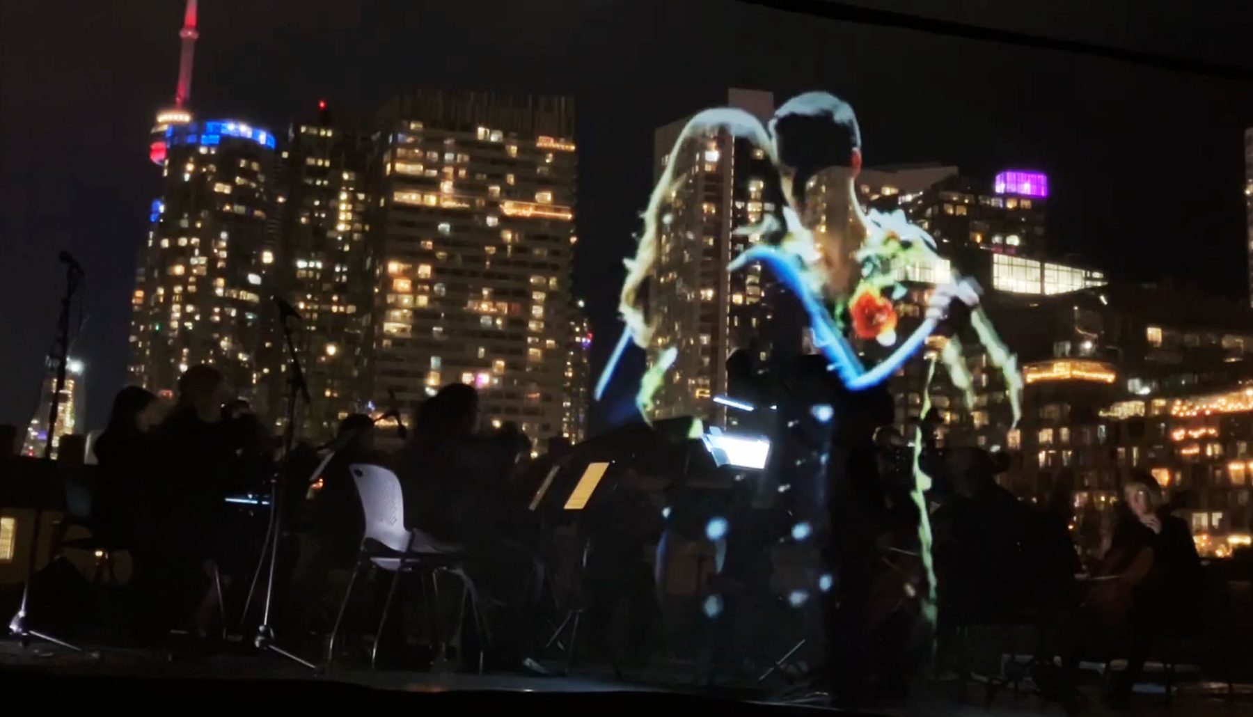 Two figures embracing, rendered in gold and blue light over the city